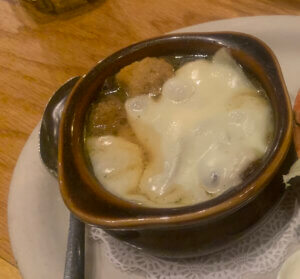 Brown soup crock on white plate with French Onion Soup