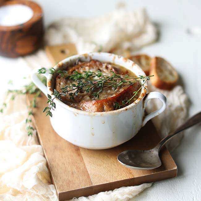 Onion soup in a white soup mug on a cutting board