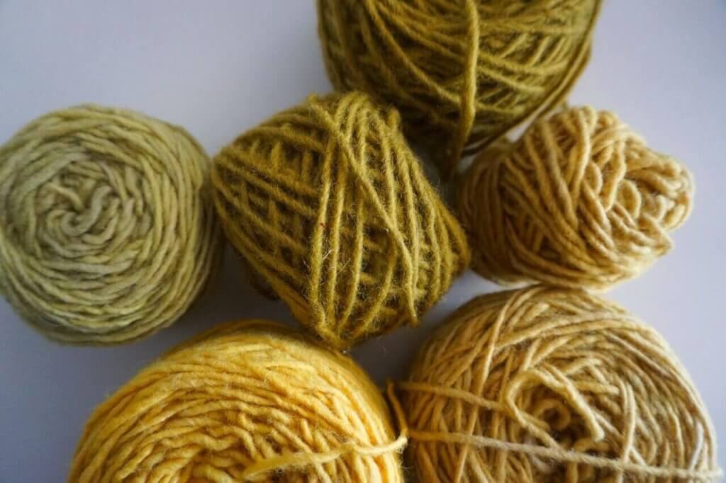 Balls of yarn dyed naturally in yellows and greens from onion skins.