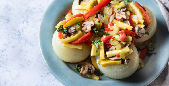 Onions stuffed with vegetables on blue plate